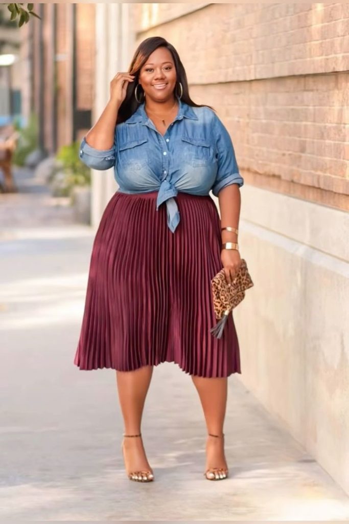 Denim jacket outfit with a burgundy pleated midi skirt and a blue denim shirt tied at the waist.