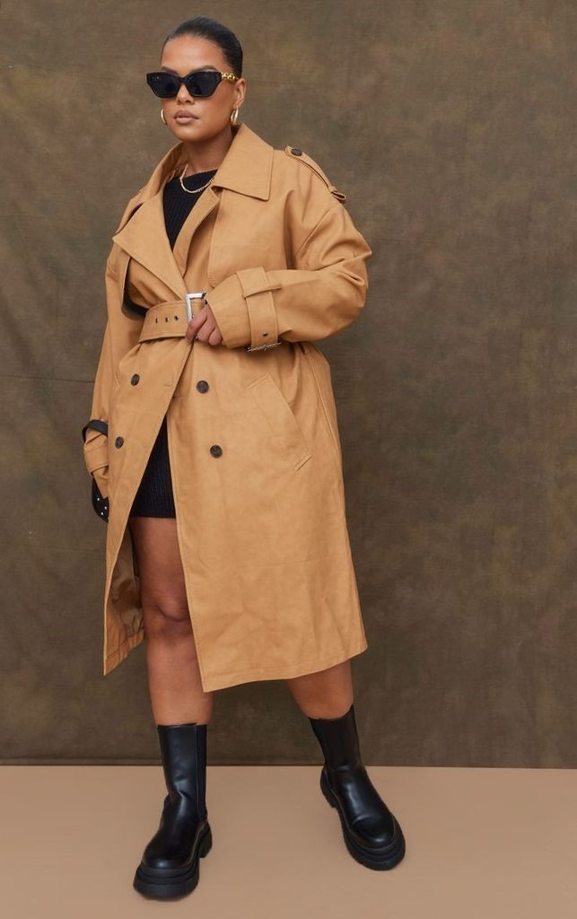 Neutral Outfit Ideas featuring a camel trench coat over a black dress, paired with black chunky boots and black sunglasses.