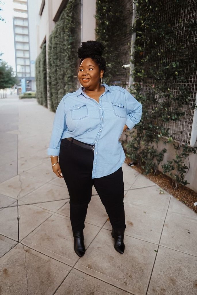 Plus size fall outfit featuring a light blue denim shirt, black trousers, and black ankle boots.