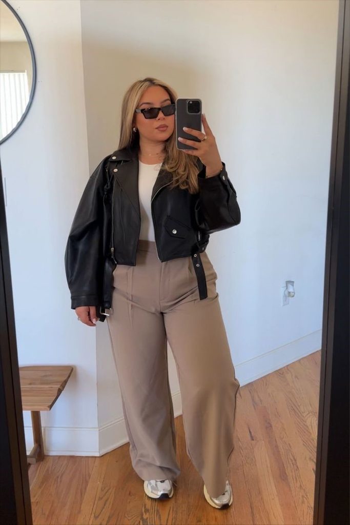 Plus size leather jacket outfit ideas featuring a black leather jacket, white top, and beige wide-leg tailored trousers