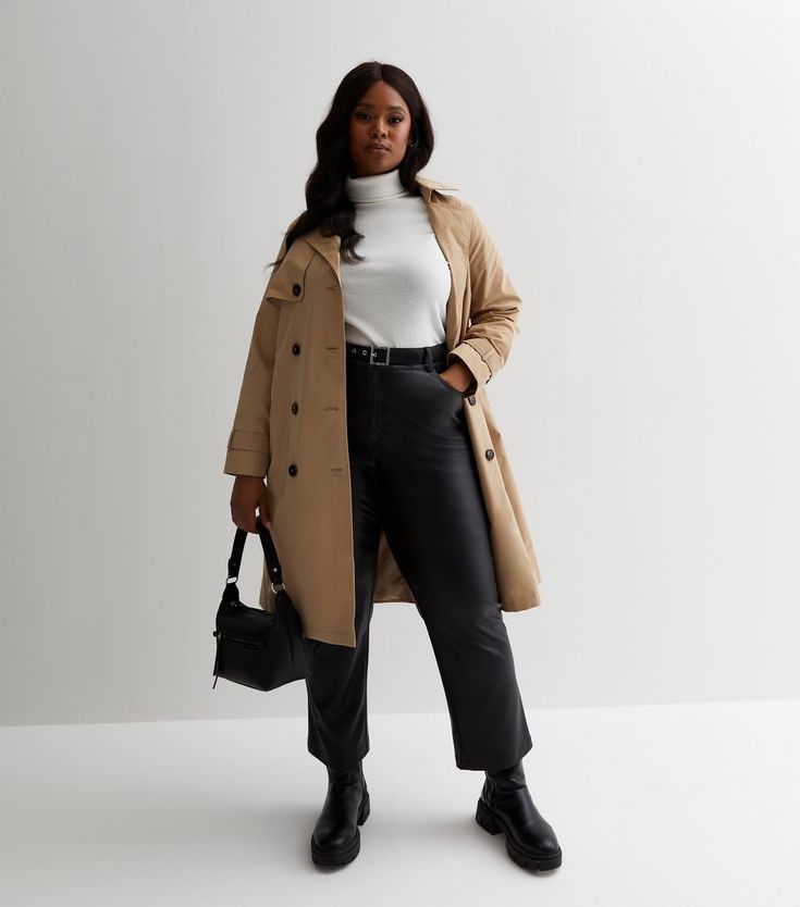 Minimalist fashion for plus size women wearing a classic camel trench coat over a simple outfit.