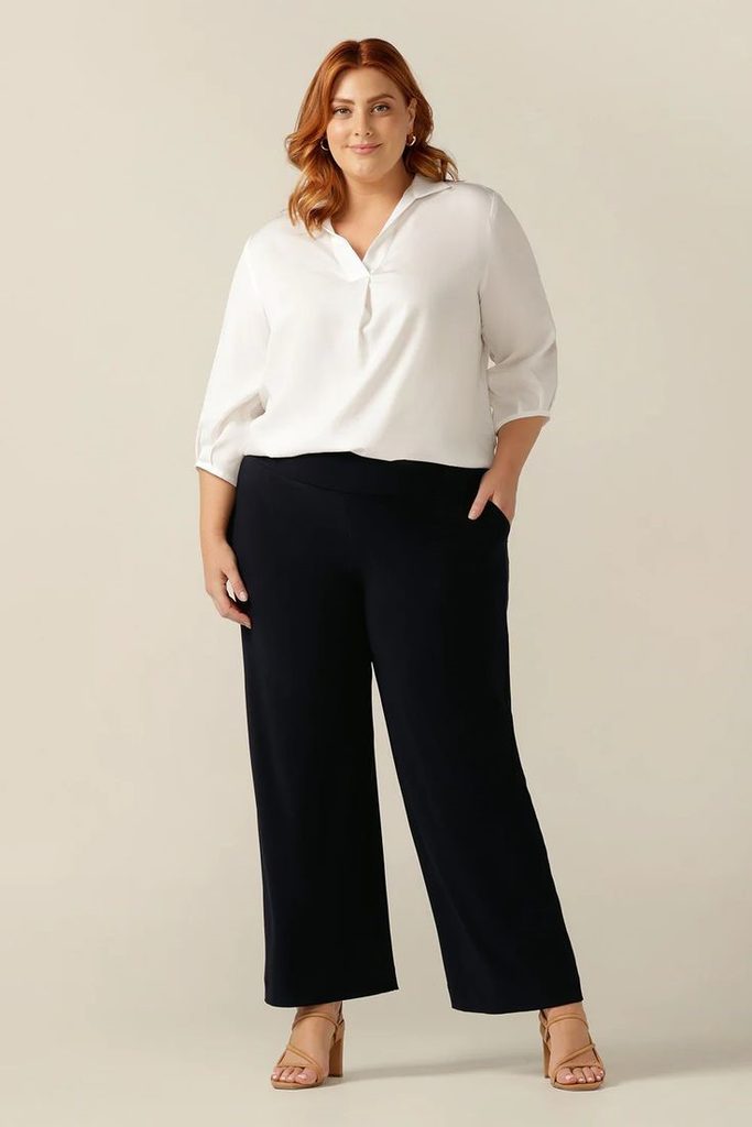 Minimalist fashion for plus size women wearing a white shirt and tailored trousers.
