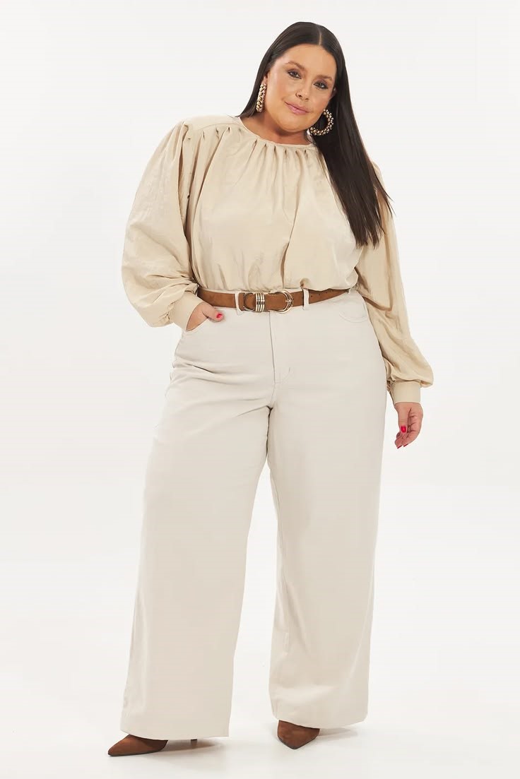 Minimalist fashion for plus size women featuring a beige blouse, cream wide-leg trousers, and a brown belt.
