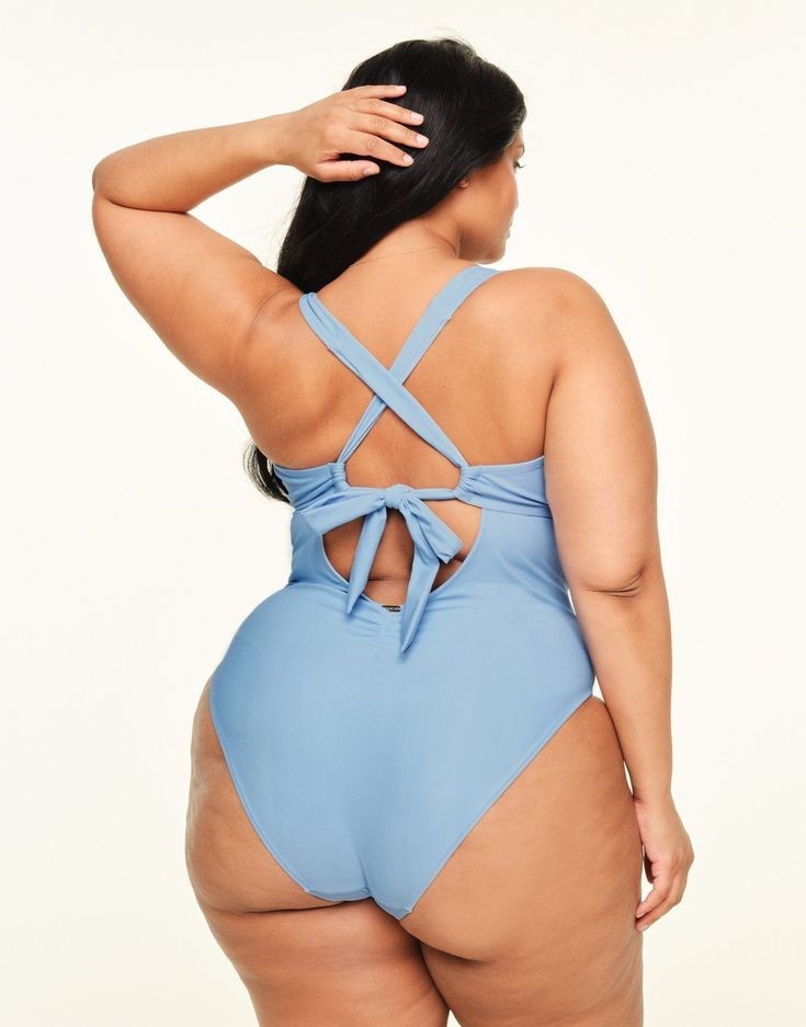 Plus size swimsuit with a low back and light blue crisscross straps with a tie detail.