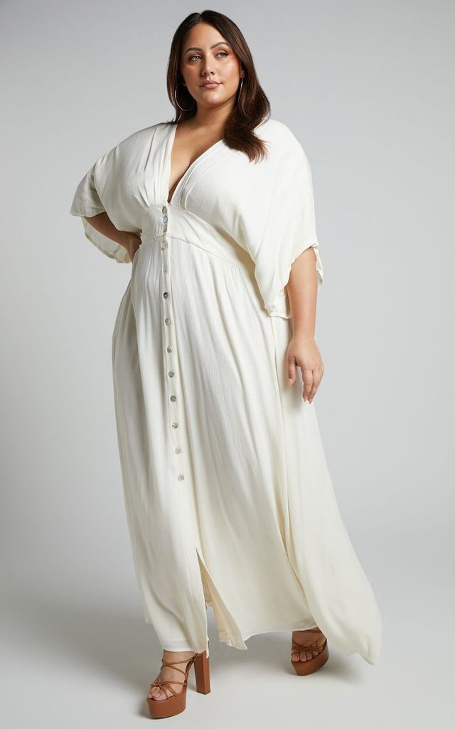 Plus size woman wearing a white button-front maxi dress with tan strappy block-heel sandals.
