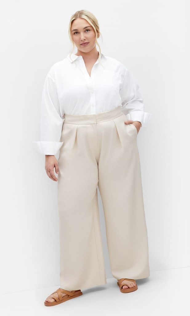 Woman wearing a white button-down shirt with cream wide-leg trousers and tan strappy sandals.